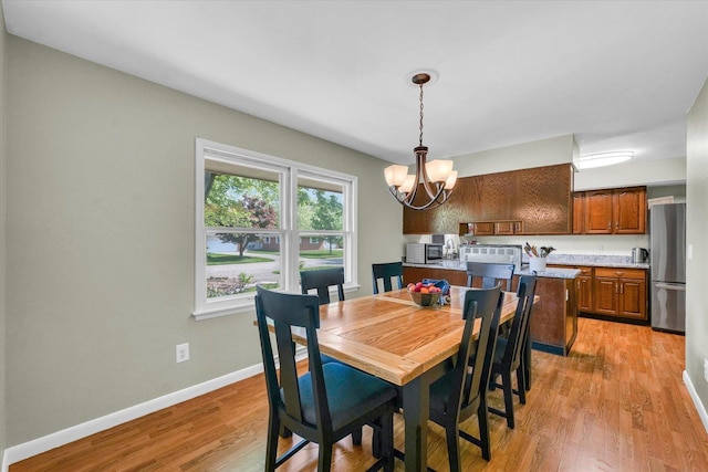 dining area with a chandelier, light wood-style floors, and baseboards