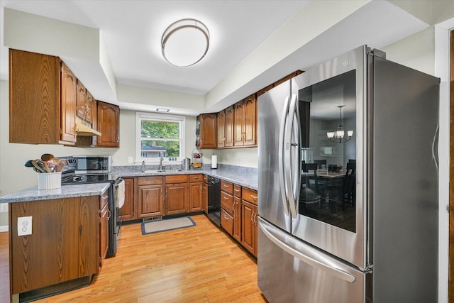 kitchen with stainless steel appliances, under cabinet range hood, a sink, brown cabinetry, and light wood-type flooring