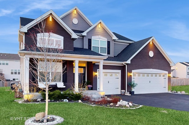 view of front facade featuring a porch, an attached garage, aphalt driveway, and a front yard