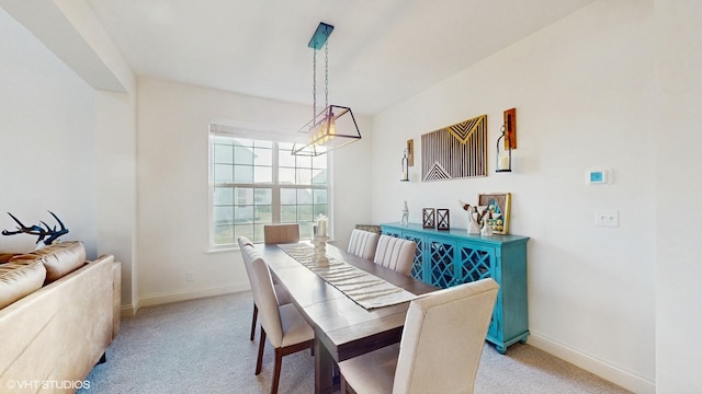 dining space with light colored carpet, baseboards, and a notable chandelier