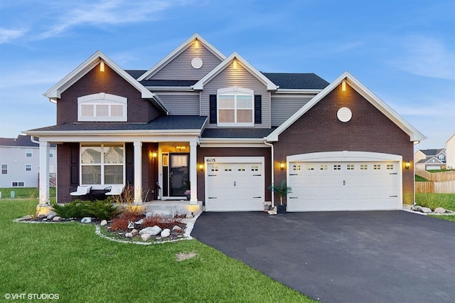 view of front facade with aphalt driveway, a front yard, covered porch, and brick siding