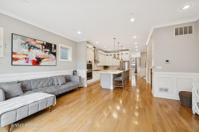 2733 N Maplewood Ave, Chicago, IL 60647 - living area featuring wainscoting, crown molding, visible vents, and light wood-style flooring
