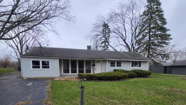 ranch-style home featuring a chimney, a front lawn, and aphalt driveway