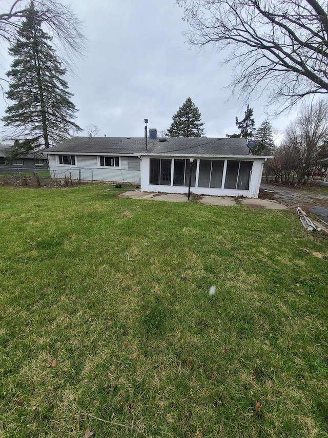 back of house with fence, a sunroom, and a lawn