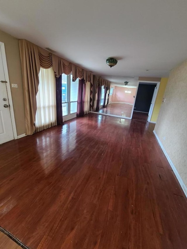 unfurnished living room with dark wood-style flooring and baseboards