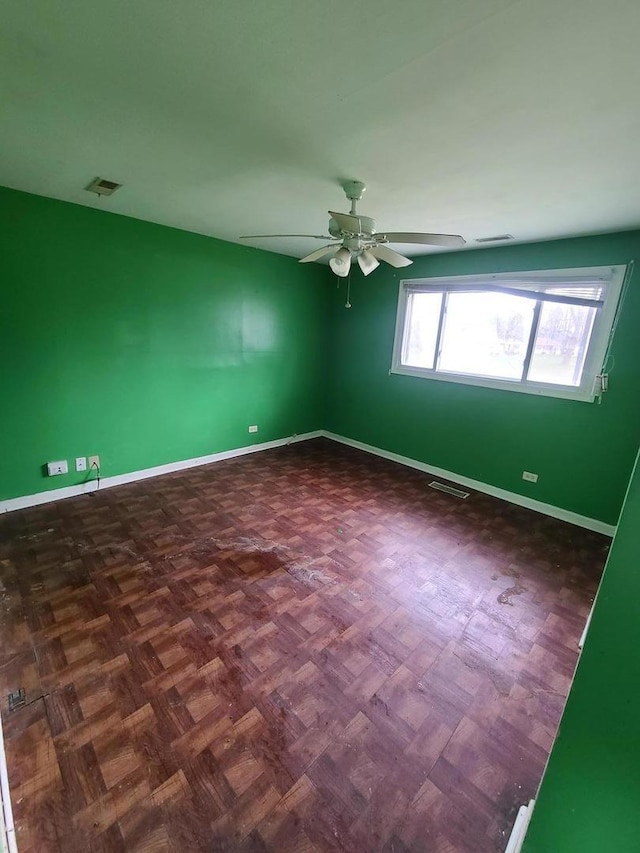 spare room with baseboards, a ceiling fan, and visible vents