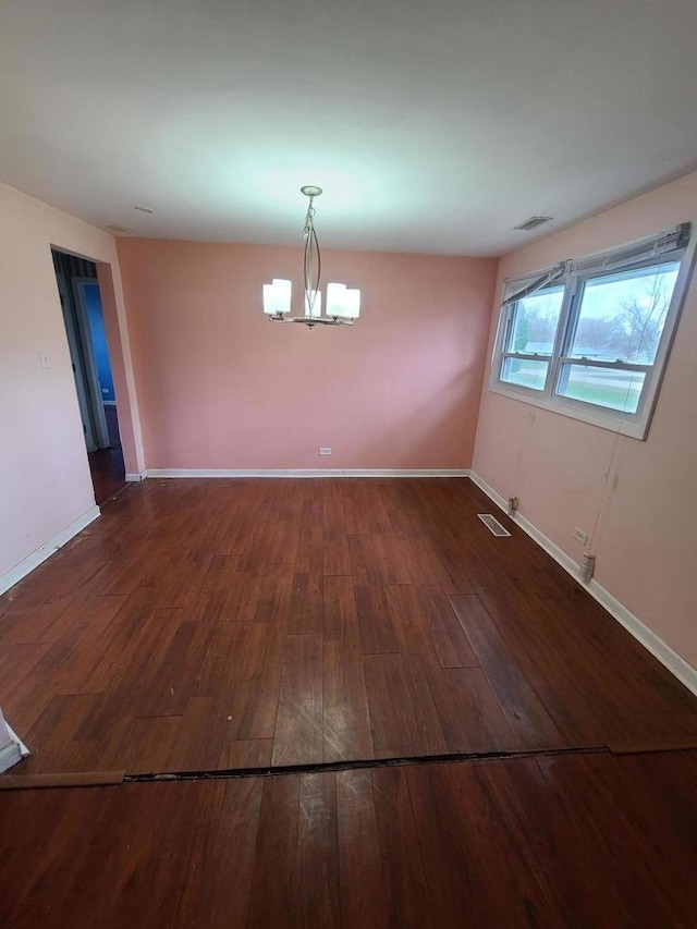 unfurnished dining area with hardwood / wood-style floors, visible vents, a notable chandelier, and baseboards