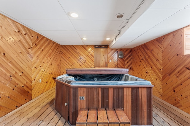 misc room with a jacuzzi, a sauna, wood walls, and light wood-style flooring