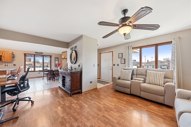 living area featuring plenty of natural light, a ceiling fan, and light wood-style floors