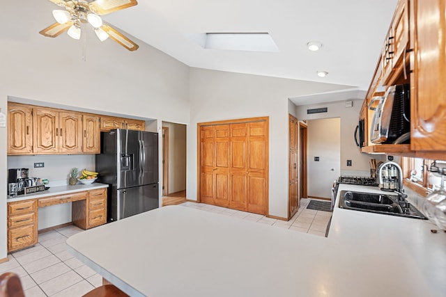 kitchen featuring a sink, built in study area, light tile patterned floors, light countertops, and refrigerator with ice dispenser