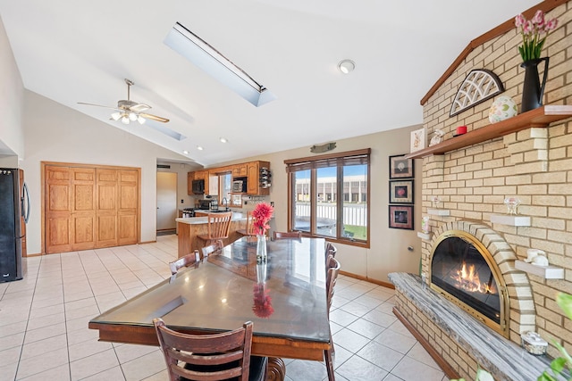 dining area with vaulted ceiling, a ceiling fan, light tile patterned floors, baseboards, and a fireplace