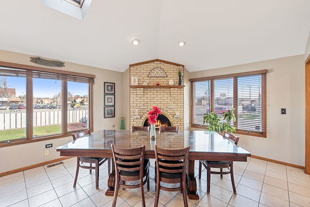 dining area featuring visible vents, lofted ceiling with skylight, light tile patterned floors, and a healthy amount of sunlight