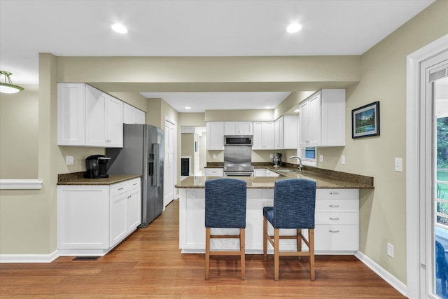 1104 Parkview Dr, Mahomet, IL 61853 - kitchen featuring appliances with stainless steel finishes, a peninsula, white cabinetry, and recessed lighting
