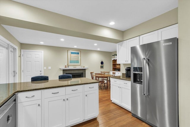 1104 Parkview Dr, Mahomet, IL 61853 - kitchen featuring stainless steel appliances, white cabinets, light wood-type flooring, dark stone countertops, and recessed lighting