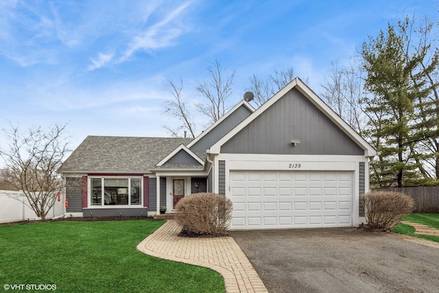 ranch-style house with a front lawn, fence, an attached garage, and aphalt driveway