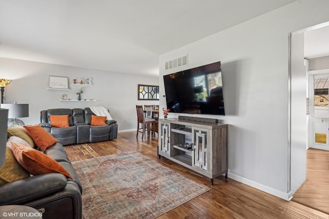 living room with visible vents, baseboards, and wood finished floors
