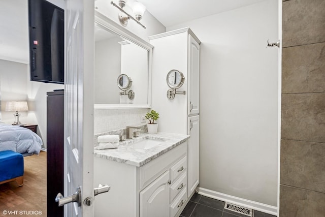 ensuite bathroom featuring tasteful backsplash, visible vents, baseboards, vanity, and tile patterned flooring
