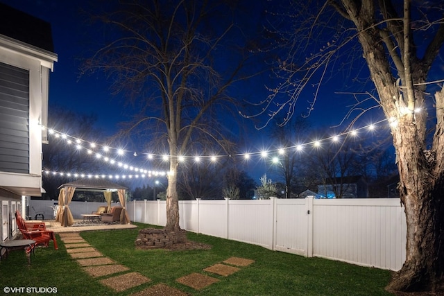 yard at night featuring a patio area and a fenced backyard