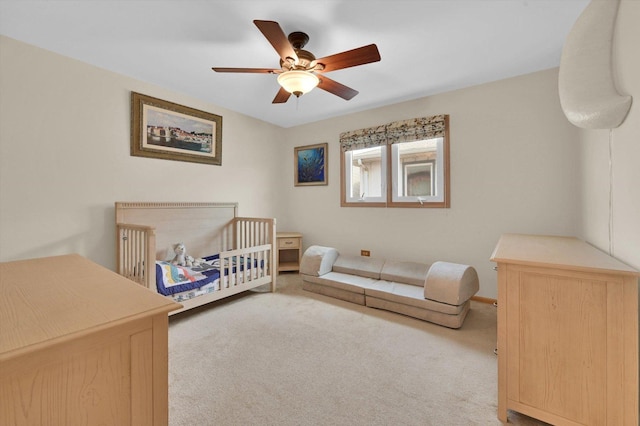 bedroom with ceiling fan, a crib, and carpet