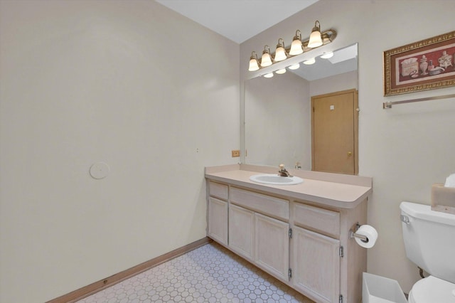 bathroom featuring vanity, toilet, baseboards, and tile patterned floors