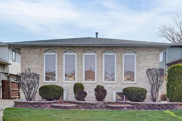 exterior space featuring a shingled roof and brick siding