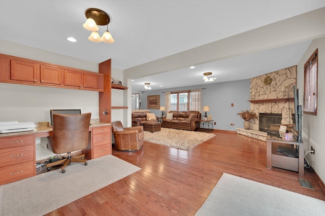 office space with built in study area, light wood-style flooring, a fireplace, visible vents, and recessed lighting
