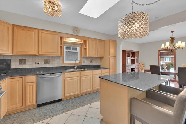 kitchen featuring backsplash, dark countertops, light brown cabinets, stainless steel dishwasher, and a sink