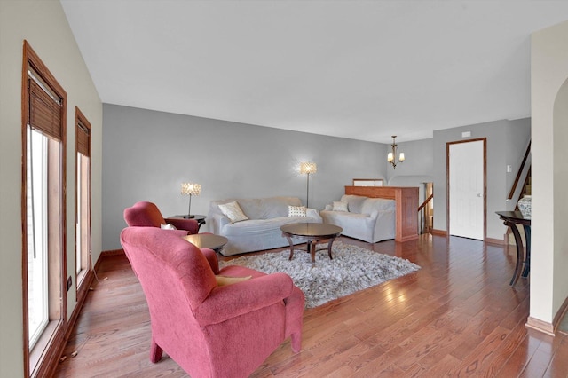 living room featuring baseboards, wood finished floors, an inviting chandelier, and a healthy amount of sunlight