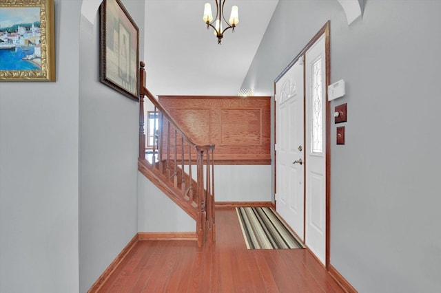 interior space with a chandelier, wood finished floors, baseboards, and stairs