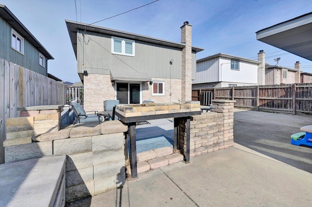 back of property featuring a fenced backyard, a chimney, and a patio