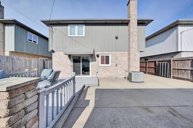 back of house featuring brick siding, a patio area, central AC, and a fenced backyard