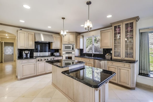 kitchen with wall chimney range hood, a center island, crown molding, decorative backsplash, and appliances with stainless steel finishes
