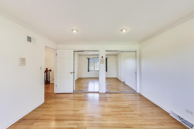 unfurnished bedroom with visible vents, baseboards, multiple closets, and light wood-style flooring