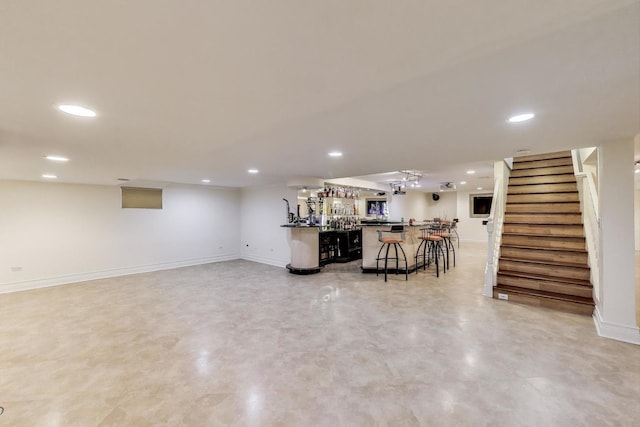 finished below grade area featuring recessed lighting, bar area, and stairs