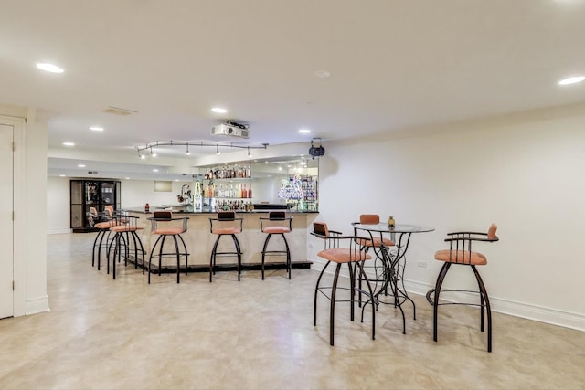 dining room with baseboards, recessed lighting, light floors, and indoor wet bar