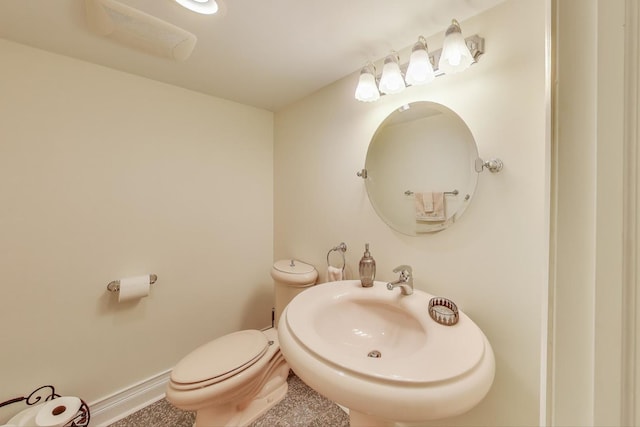 half bathroom featuring baseboards, a sink, and toilet