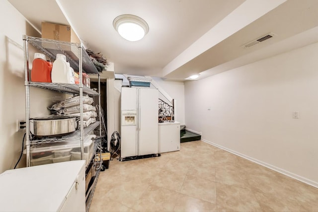 finished below grade area with washer / clothes dryer, baseboards, white fridge with ice dispenser, and visible vents
