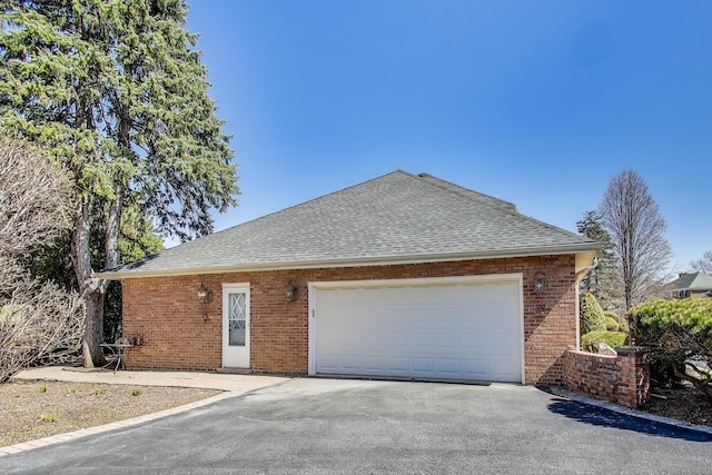view of side of property featuring brick siding, driveway, and a shingled roof