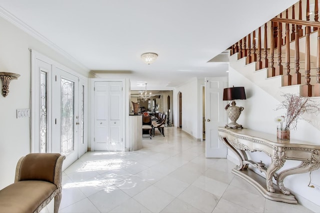 entrance foyer with a chandelier, light tile patterned flooring, ornamental molding, and stairs