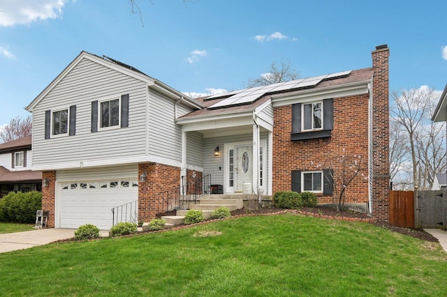 split foyer home with a chimney, fence, solar panels, brick siding, and a front yard
