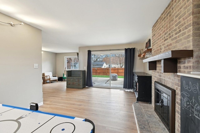 interior space featuring baseboards, a brick fireplace, and light wood-type flooring