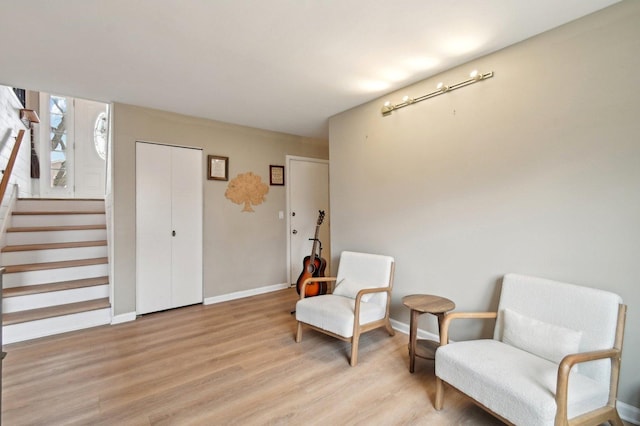 sitting room featuring light wood-style floors, stairway, and baseboards