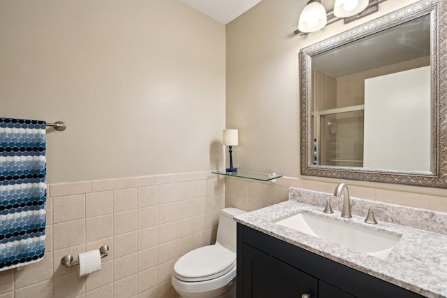bathroom featuring a wainscoted wall, toilet, tile walls, a stall shower, and vanity