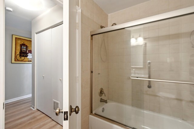 full bathroom with baseboards, wood finished floors, and shower / bath combination with glass door