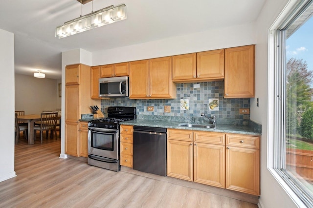 kitchen featuring decorative backsplash, a wealth of natural light, appliances with stainless steel finishes, and light wood-style floors
