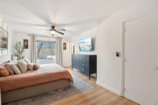 bedroom with light wood-type flooring, a ceiling fan, and baseboards