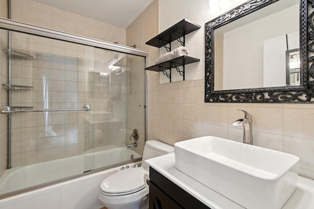 full bath featuring tile walls, vanity, bath / shower combo with glass door, and toilet