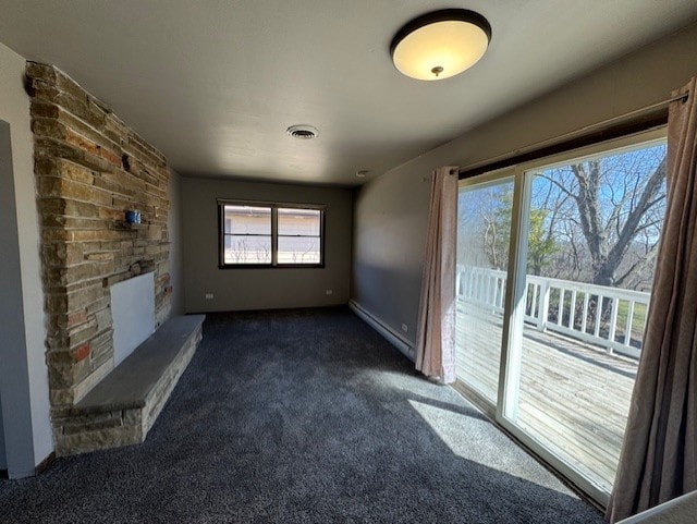 707 Crestview Dr, Ingleside, IL 60041 - unfurnished living room featuring a baseboard heating unit, visible vents, a stone fireplace, and dark carpet