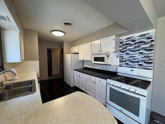 707 Crestview Dr, Ingleside, IL 60041 - kitchen featuring visible vents, a sink, white appliances, white cabinetry, and decorative backsplash