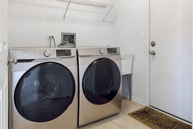 clothes washing area with laundry area, light tile patterned floors, baseboards, and washing machine and dryer